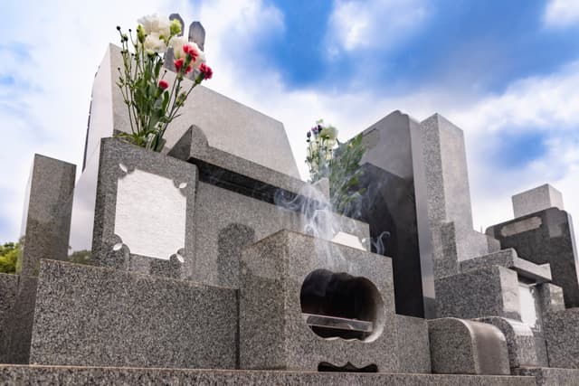 お墓に供えられた仏花と立ち上る線香の煙